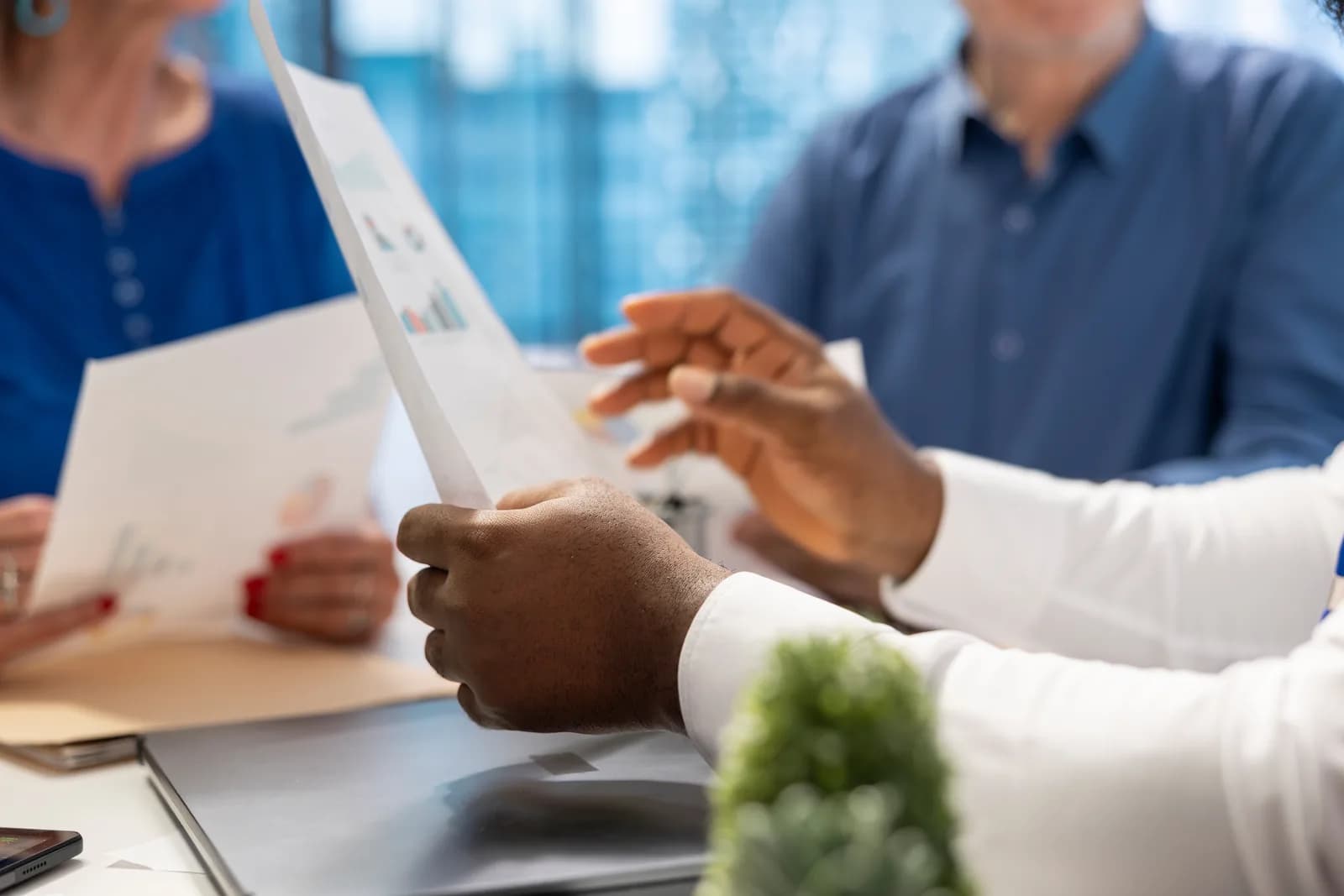 Three people at a table reviewing a printed chart and papers