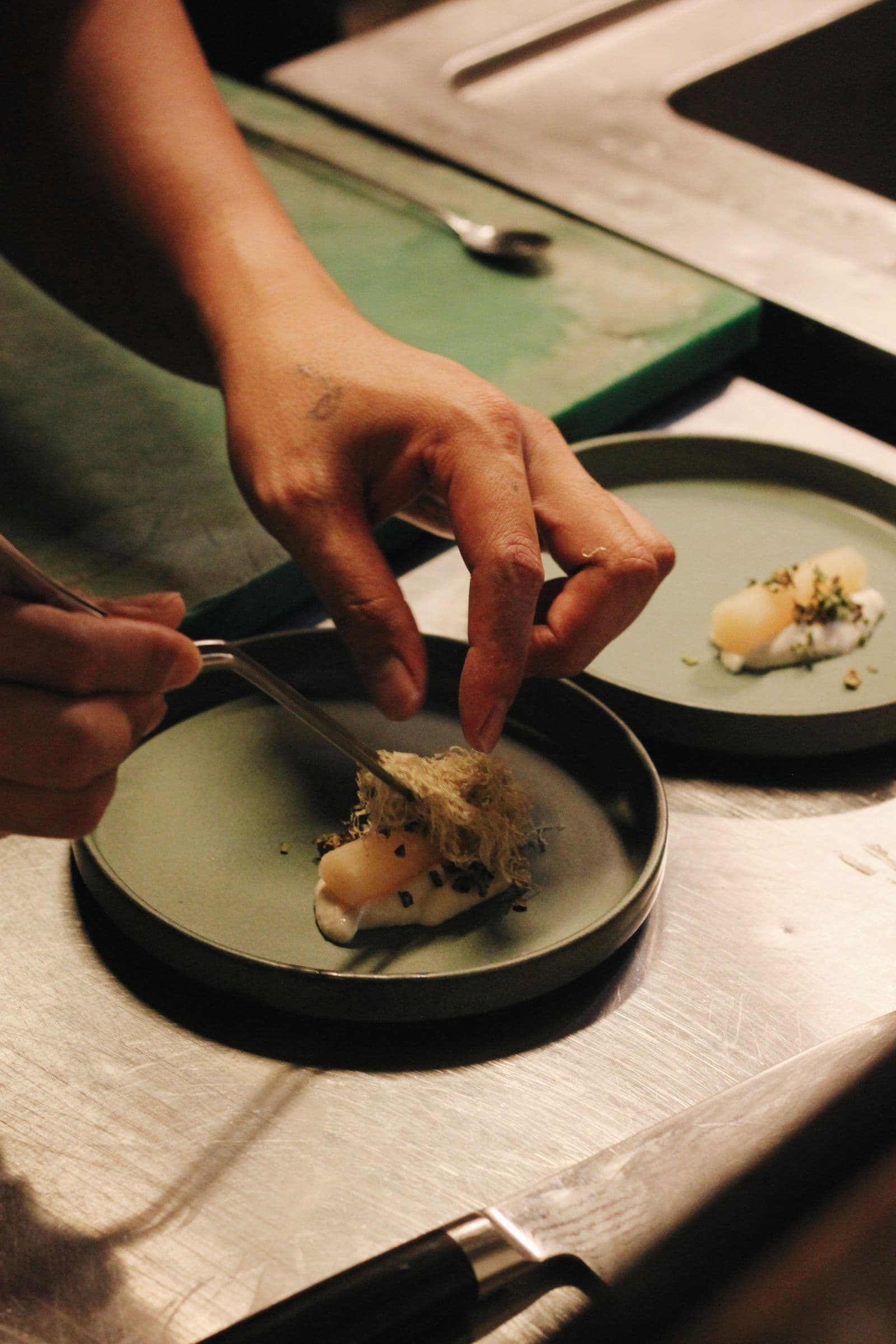 Private chef plating a fine dining dish by hand